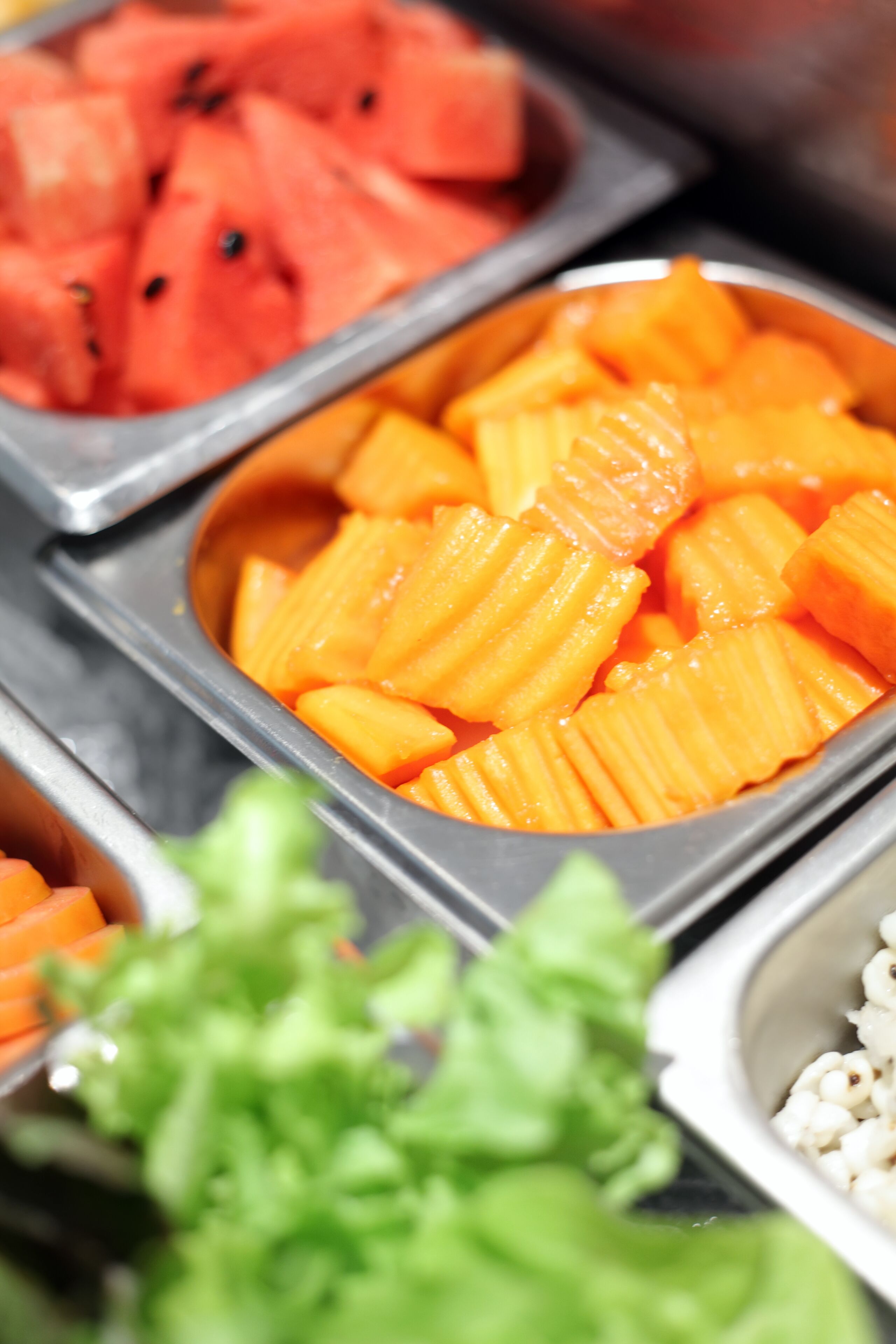 A buffet with various food items including watermelon, orange slices, and pasta.