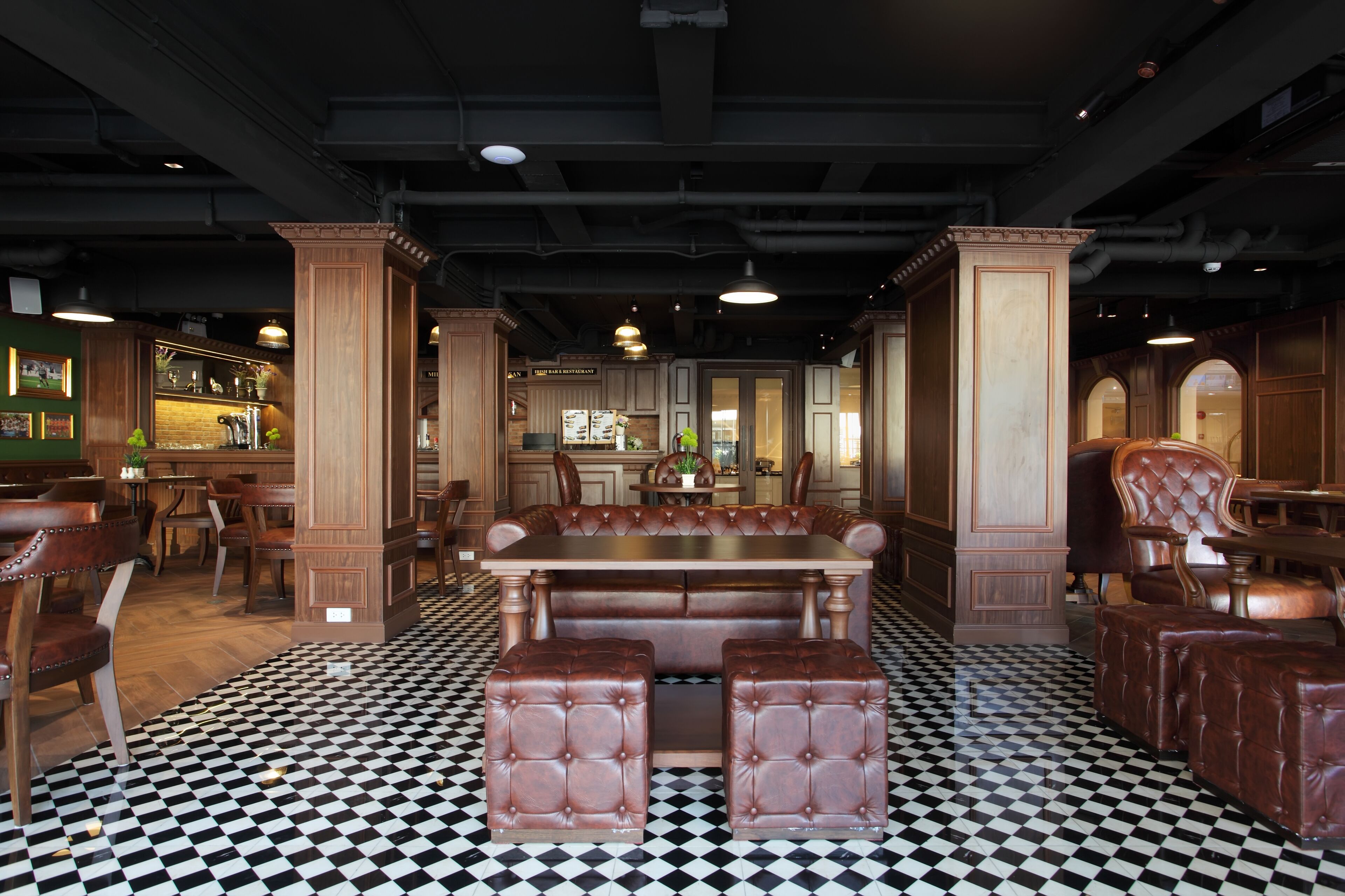 Ein Restaurant mit Schachbrettmuster-Boden, Holzmöbeln und einer Bar im Hintergrund.