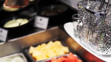 Un bufé con diversas opciones de comida, incluyendo frutas, verduras y ensaladas.