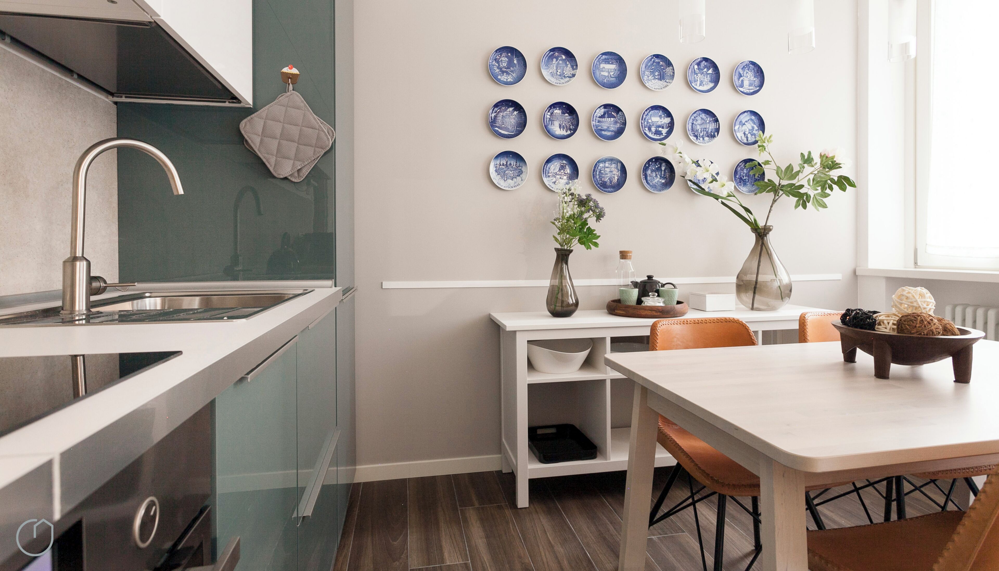Una cocina moderna con un lavamanos de acero inoxidable, una encimera blanca y un comedor con mesa y sillas.