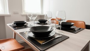 Een eettafel gedekt met zwarte kommen, wijnglazen en bestek op zwarte placemats.