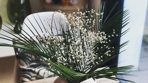 A round, textured vase with white flowers and green foliage on a wooden table. - La Maison Odeia (Bordeaux)