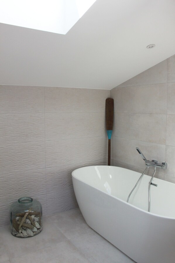 A modern bathroom with a freestanding bathtub, a wooden paddle, and a glass jar with stones. - La Maison Odeia (Bordeaux)