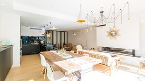 A modern kitchen with a wooden table, white chairs, and pendant lighting. - La Maison Odeia (Bordeaux)