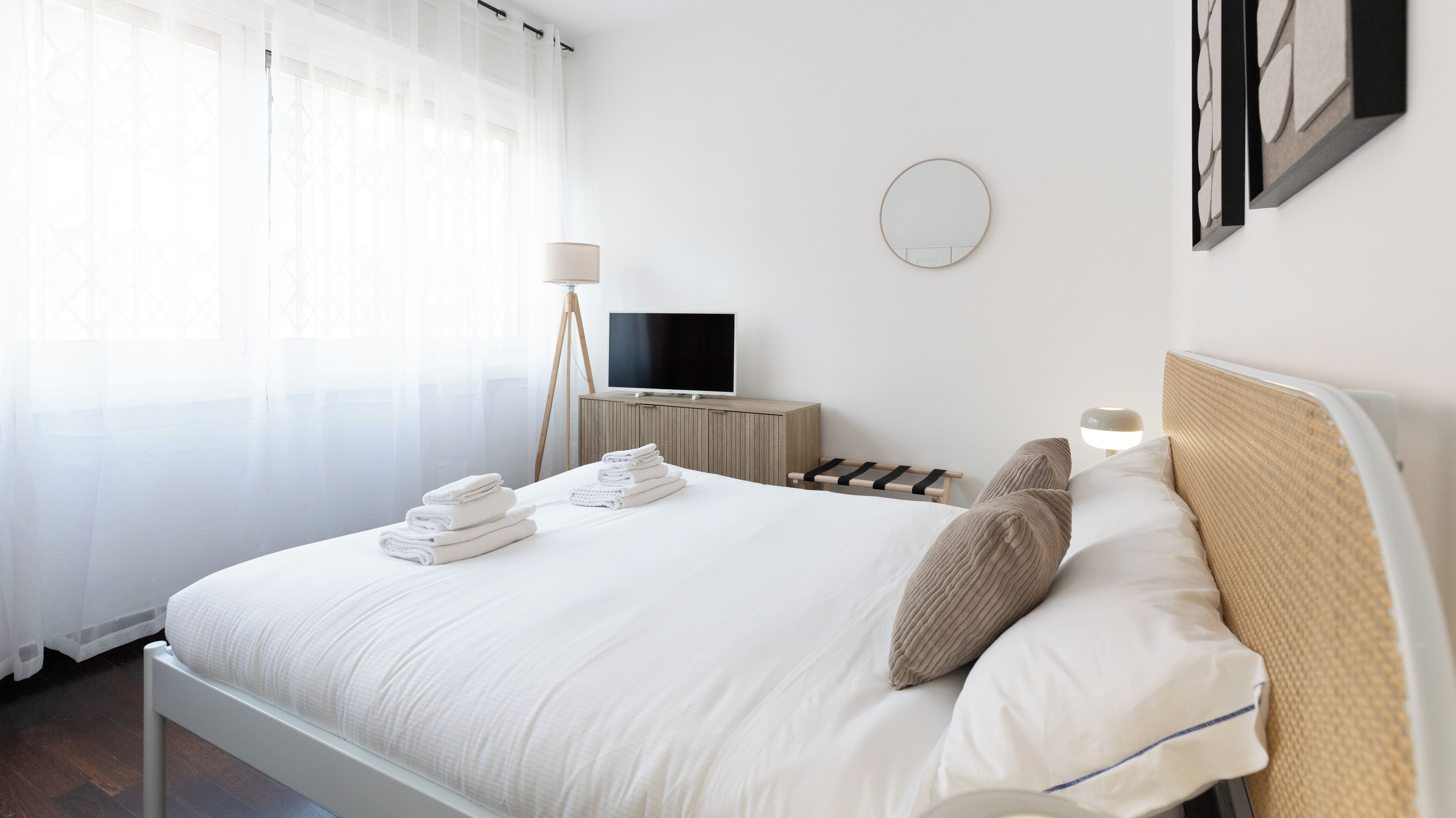 Habitación de hotel con cama, televisión, mesita de noche y lámpara.