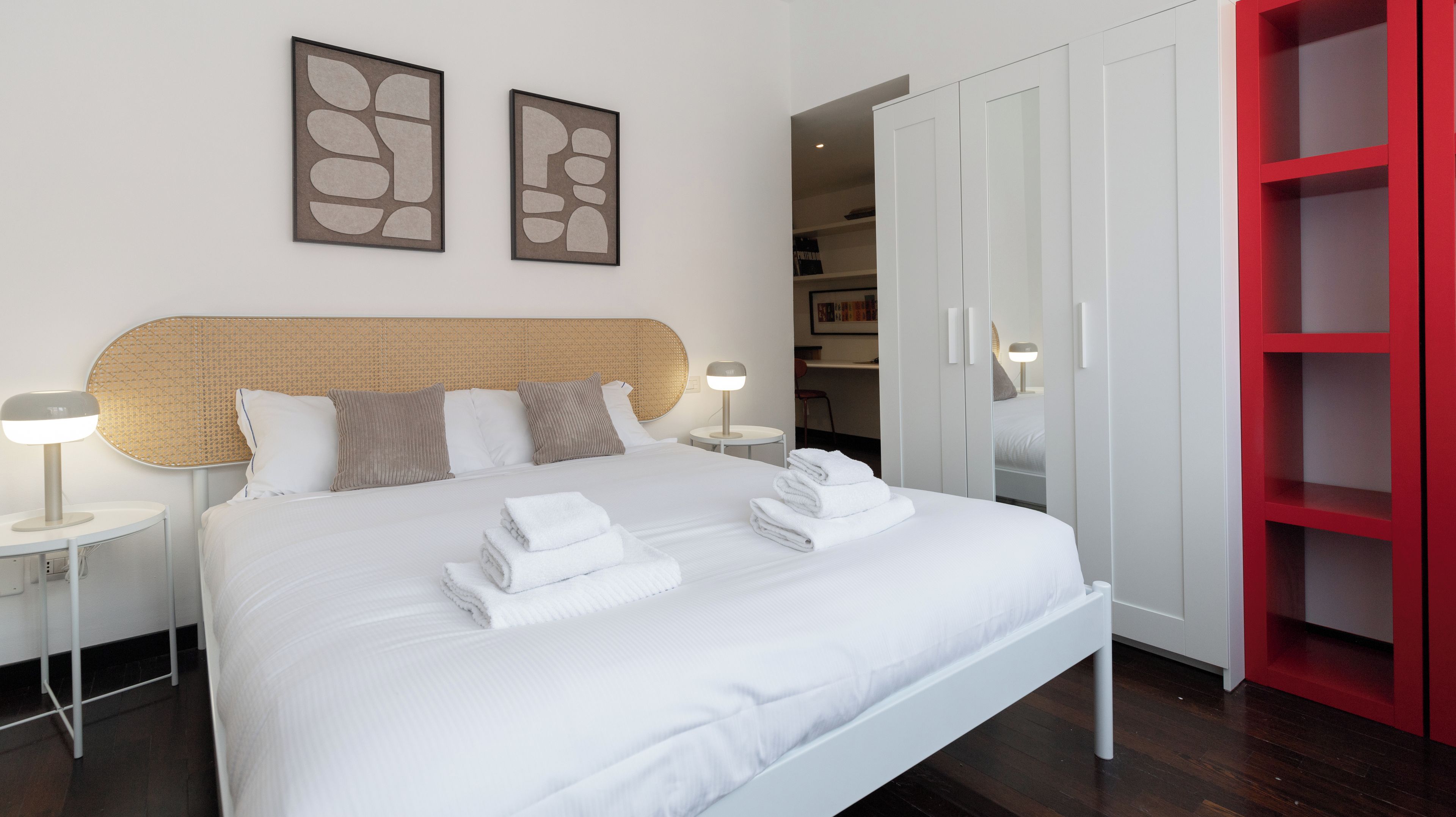 A hotel room with a bed, two bedside tables, a headboard, and a wardrobe.