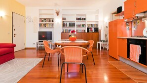 A modern kitchen with a dining area, wooden flooring, and a red sofa. - Italianway   - Vallazze 87 (Milan)