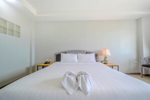 A hotel room with a large bed, a bedside lamp, a telephone, and a chair. - BCP Hotel (Ban Chang)