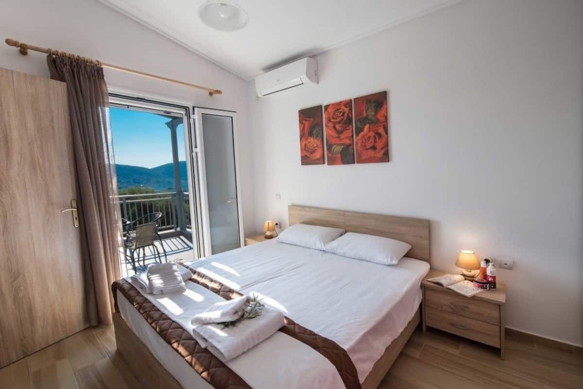 Una habitación de hotel con cama, mesita de noche, ventana con vistas y una pared con tres cuadros.