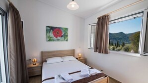 Quarto de hotel com uma cama grande, duas mesas de cabeceira com abajures, uma janela com cortinas e um quadro de uma flor na parede.