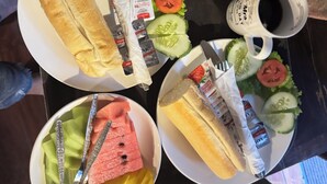 Een tafel met ontbijtartikelen, waaronder croissants, een salade met komkommer en tomaat, en twee kopjes koffie.