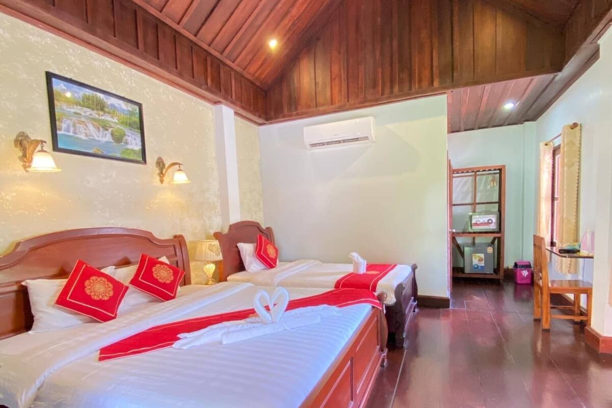 A wooden-paneled room with a bed, a ceiling fan, and an air conditioning unit.