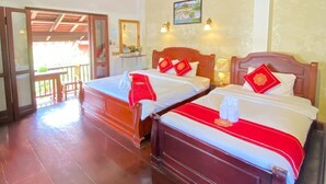 Een hotelkamer met twee houten bedden, een plafondventilator en uitzicht op buiten.