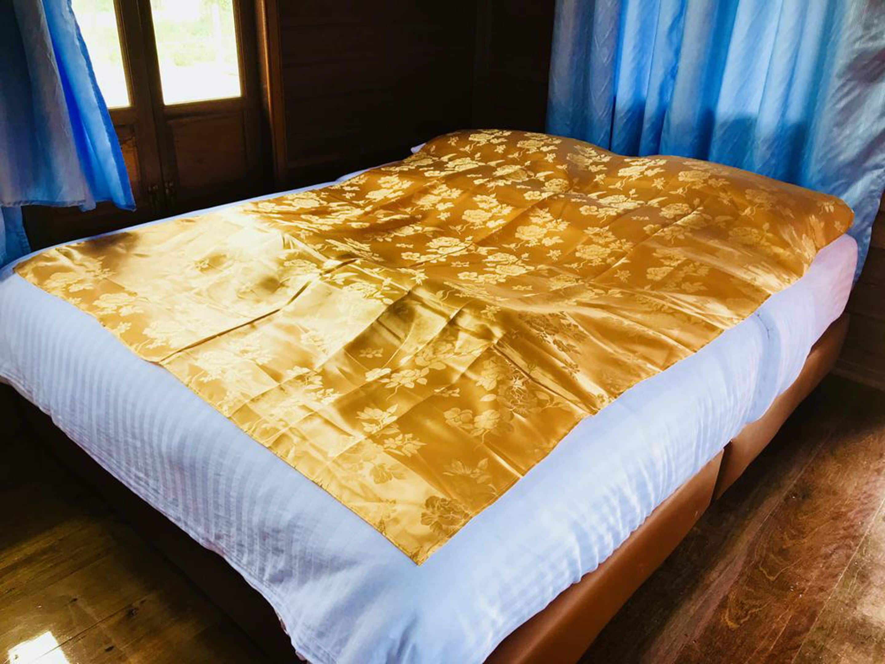 A bed with a floral patterned bedspread and a white pillow.