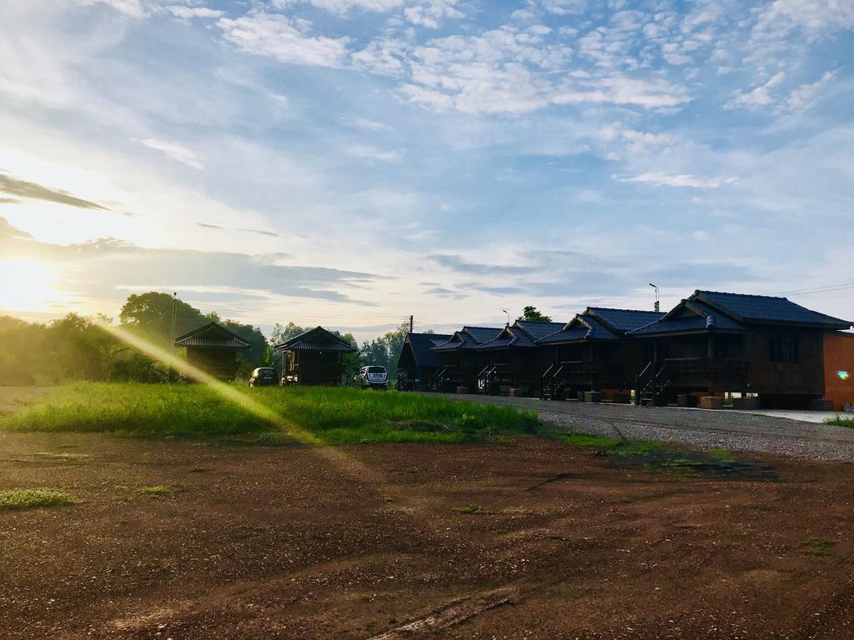 A row of traditional wooden houses with a dirt path in front.