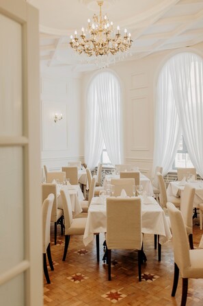 A formal dining room with tables set for service, large windows with sheer curtains, and a chandelier. - Dom Sivre Boutique Hotel (Samara)