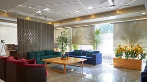 A modern living room with a large window, a wooden coffee table, and two sofas. - Hotel Golf View Suites (Gurugram)