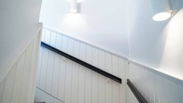 A staircase with white paneling and black handrails.