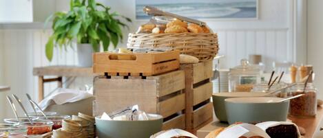 Un buffet proposant une variété de plats, notamment du pain, des pâtisseries et de la viande, disposés sur un comptoir en bois.