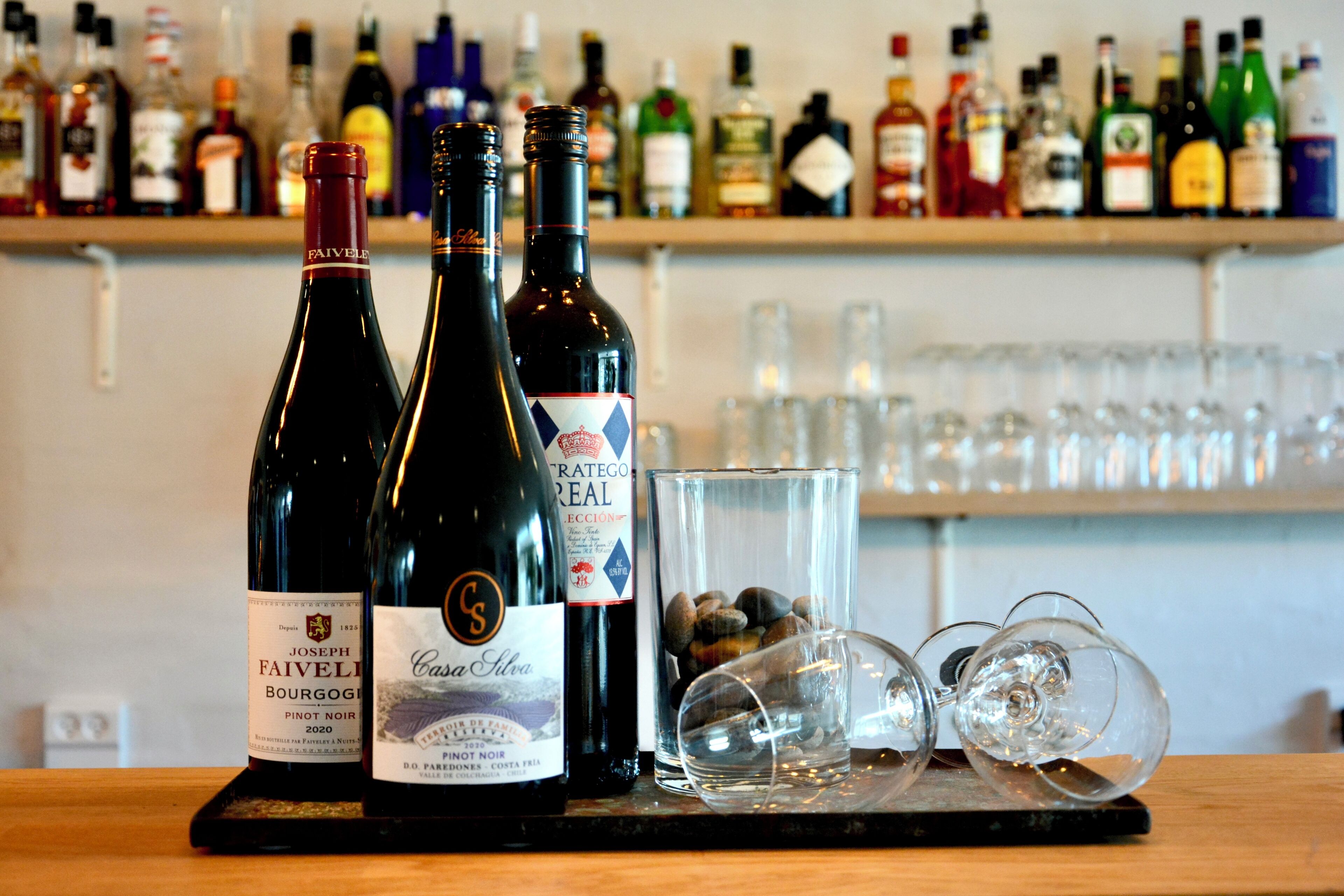 A bar counter with bottles of wine and glasses.