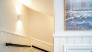 Portaat, joissa on kaide, seinään kiinnitetty valaisin ja kehystetty kuva merimaisemasta.
