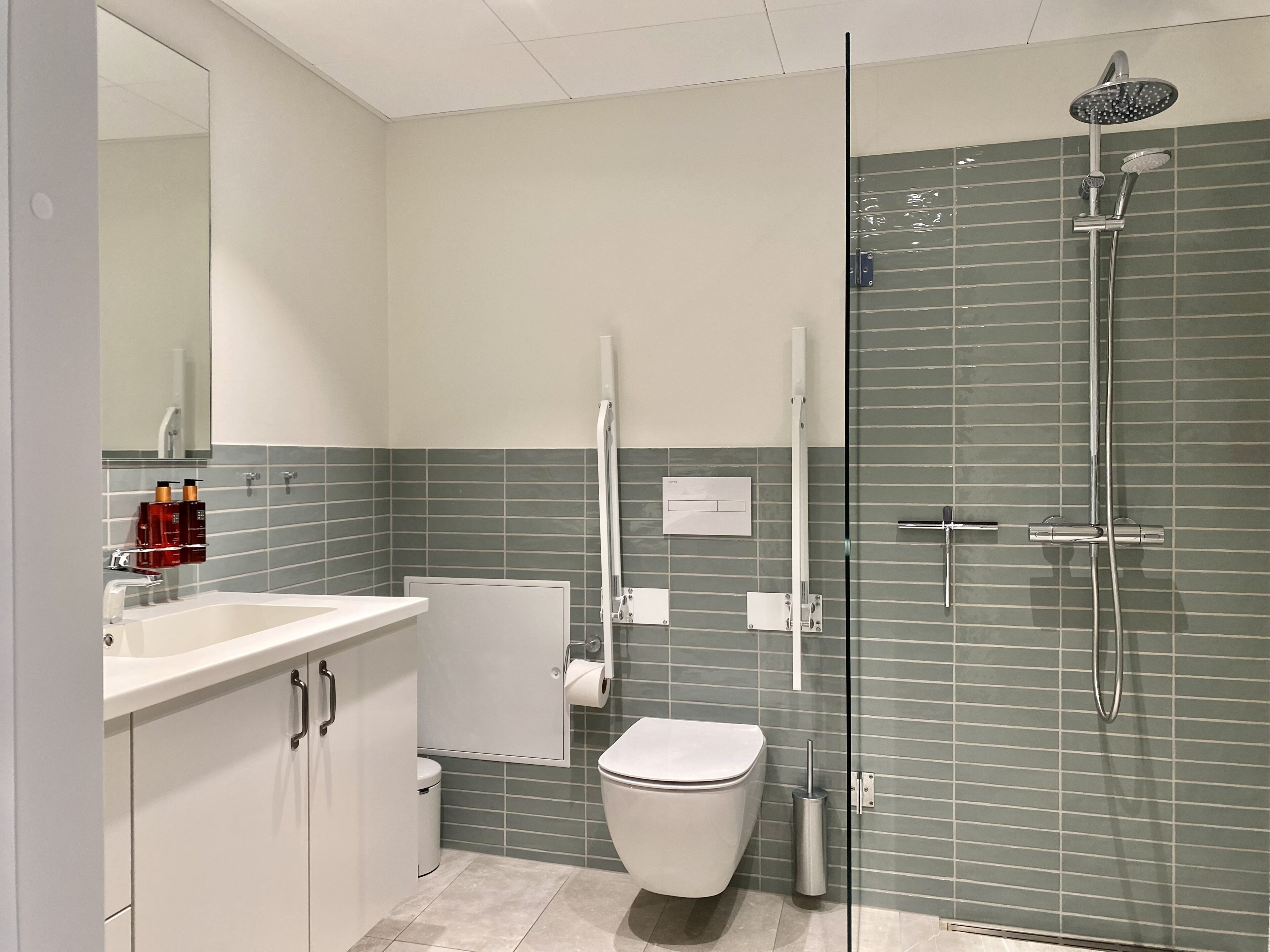 Un baño moderno con ducha de vidrio, inodoro blanco y lavamanos con espejo.