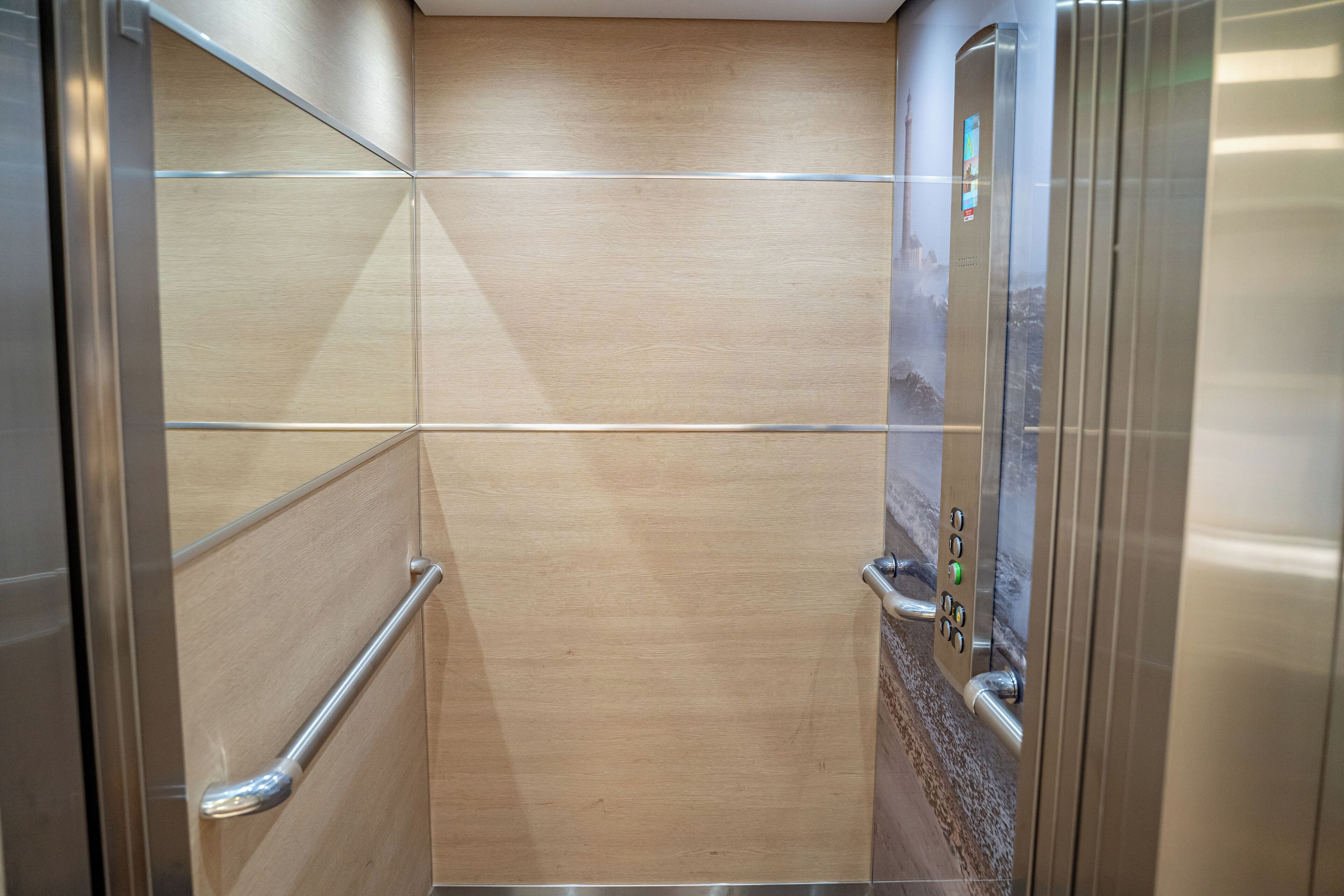 An elevator with metallic walls and a wooden panel design.
