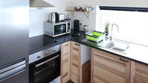 A compact kitchen with a refrigerator, stove, oven, microwave, and a sink. - Blue View Cabin 6A with Hot Tub (Bláskógabyggd)
