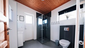 A modern bathroom with a glass-enclosed shower, a white toilet, and a black tiled wall. - Blue View Cabin 6A with Hot Tub (Bláskógabyggd)