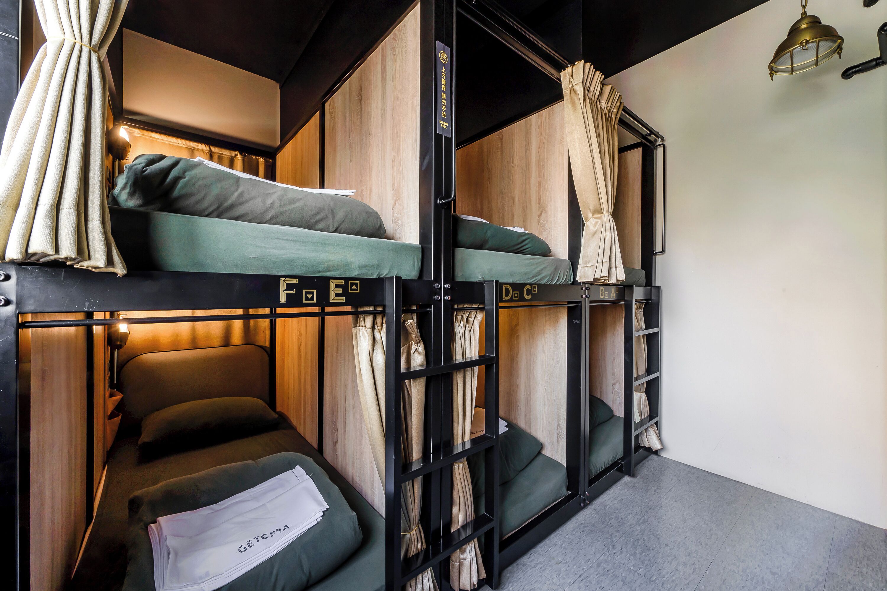 A bunk bed room with a wooden headboard, a small table, and a hanging light fixture.
