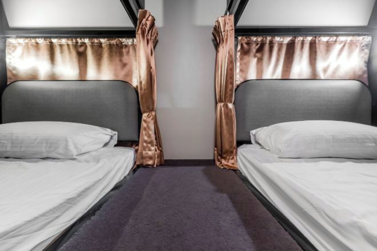 A room with two single beds, a purple carpet, and curtains.