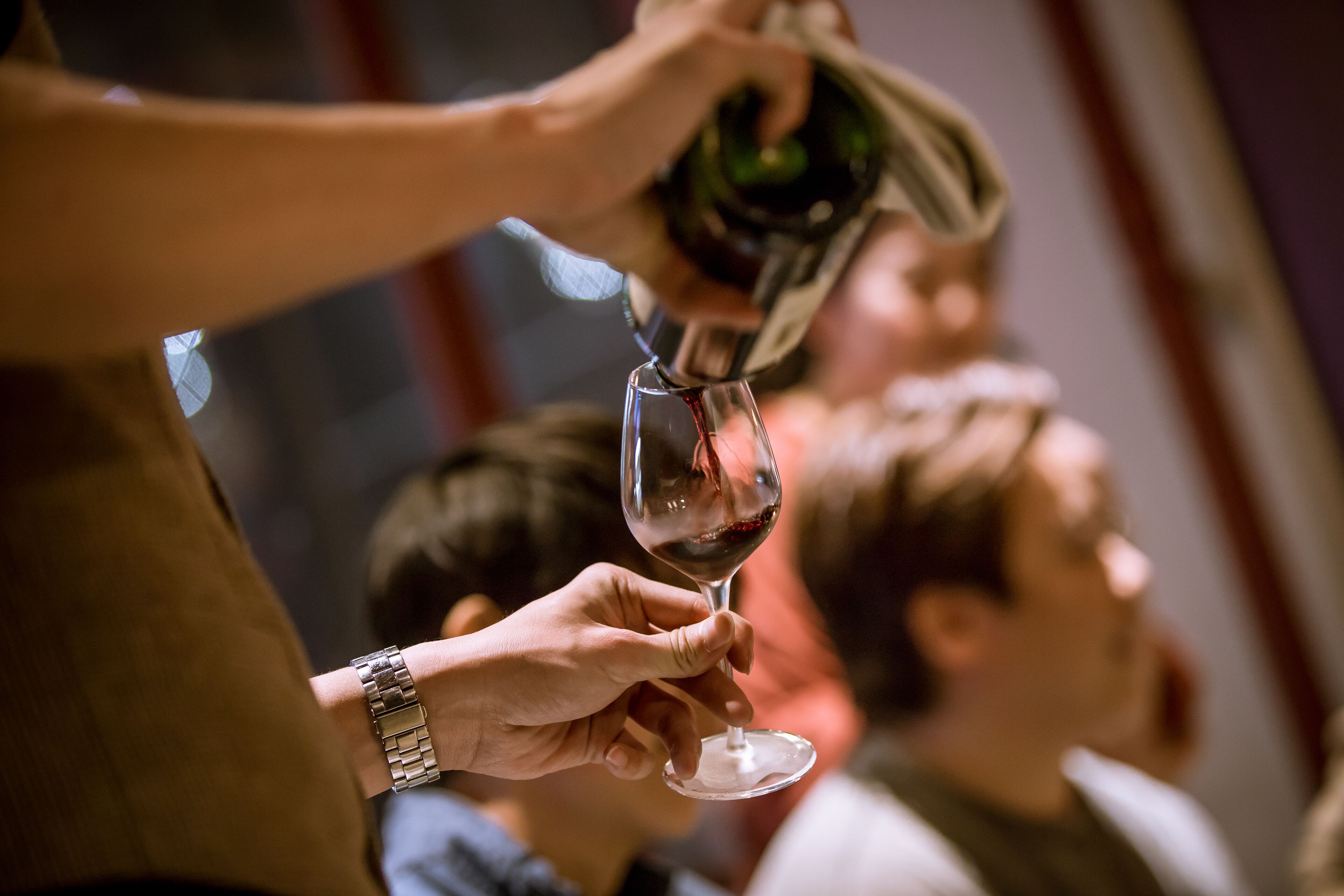 A person pouring wine into a glass.