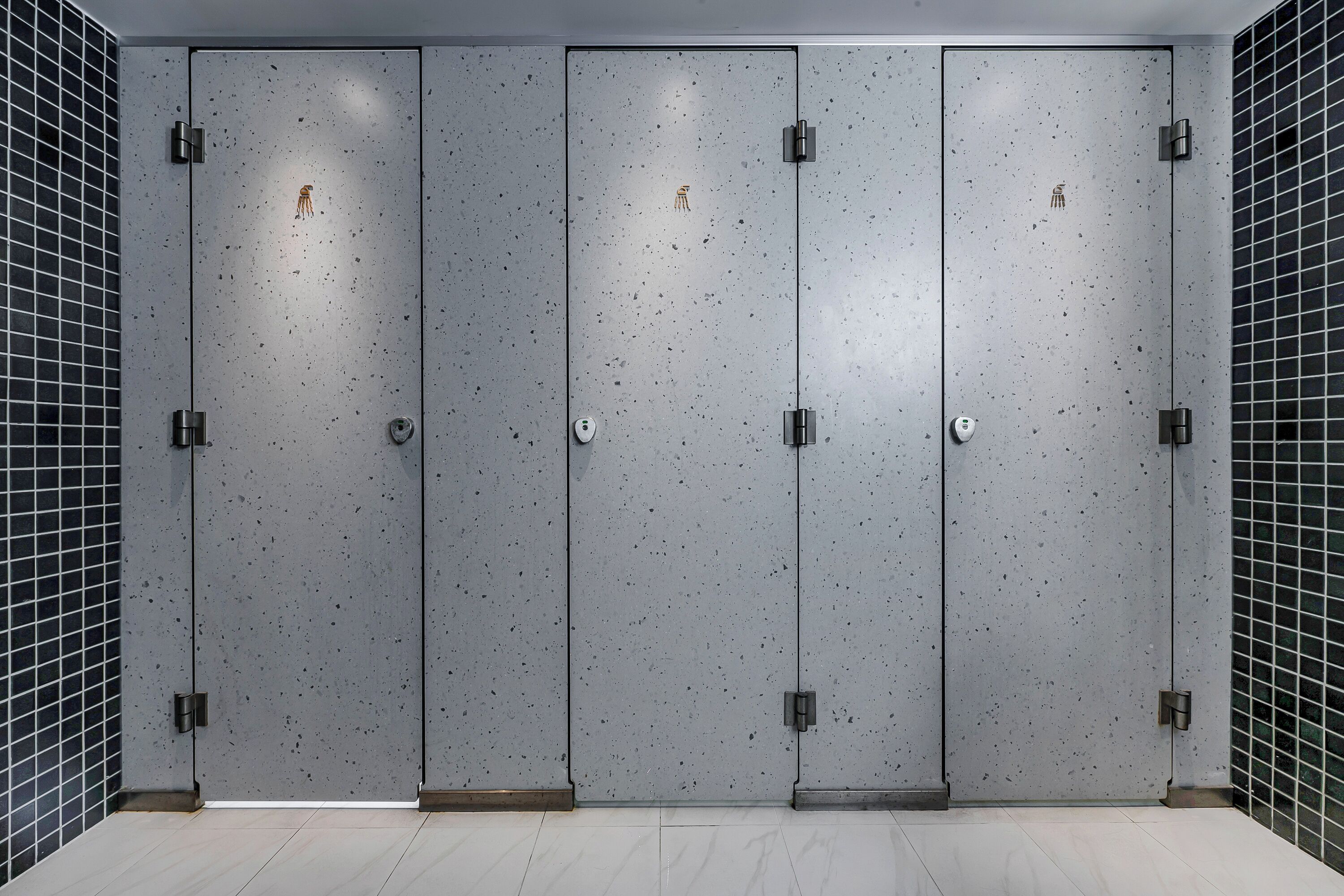A row of four grey lockers with a speckled texture, each with a small, round, gold-colored lock.