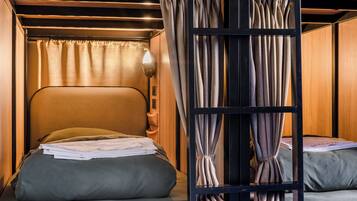 A neatly made bed with a headboard, a bedside lamp, and a curtain.