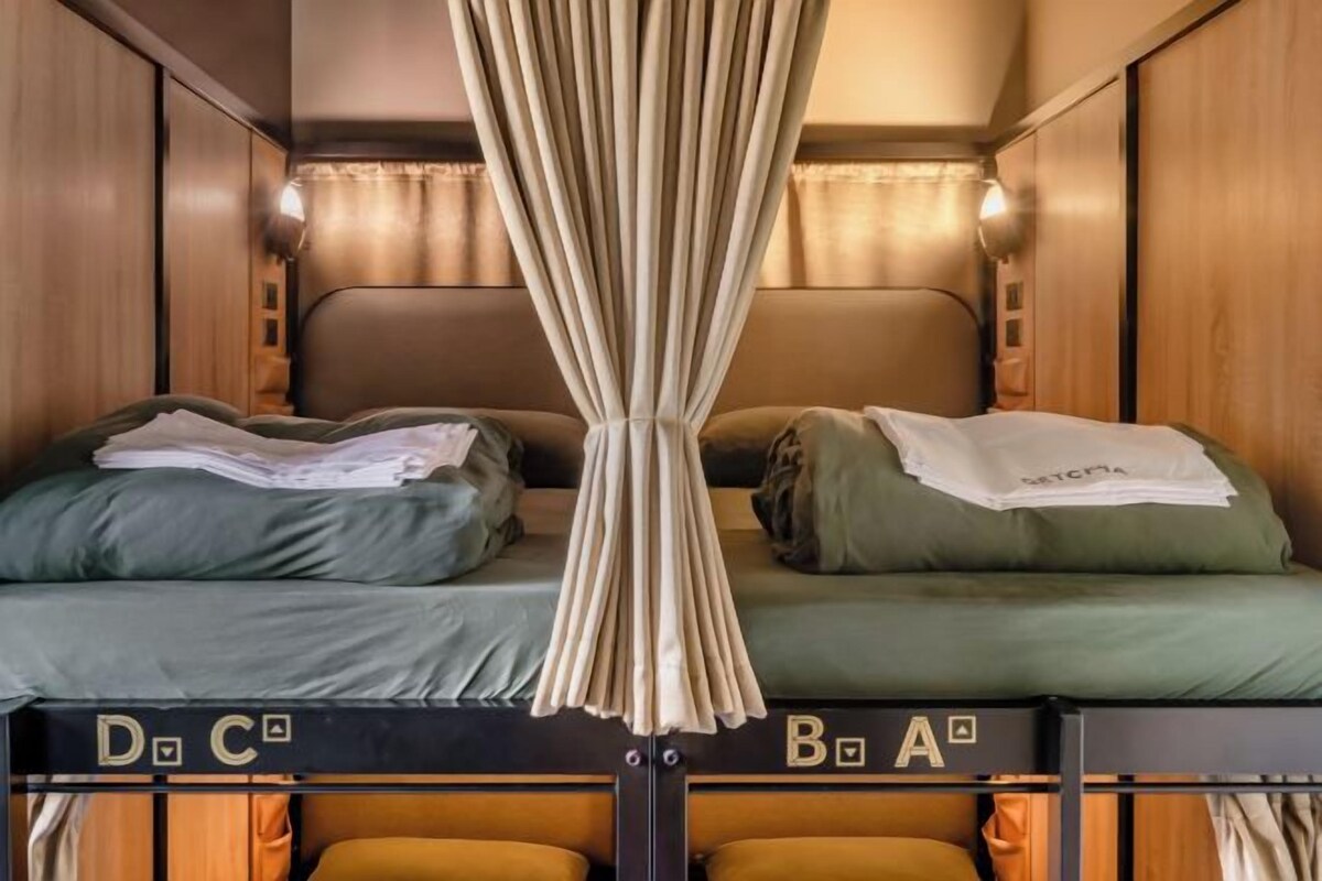 Una cama litera con dos niveles, cada uno con almohada y manta.
