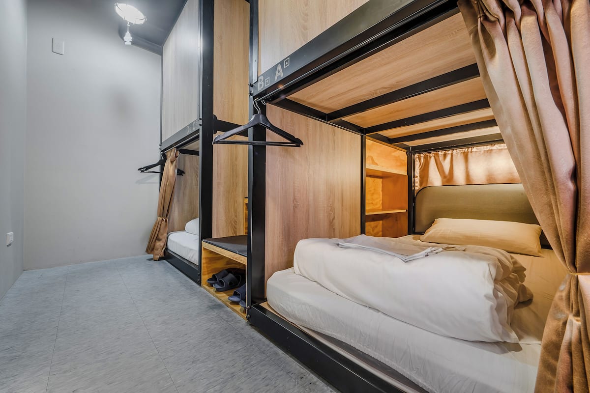 Quarto com beliche, cabeceira de madeira, luminária pendente e sapateira.