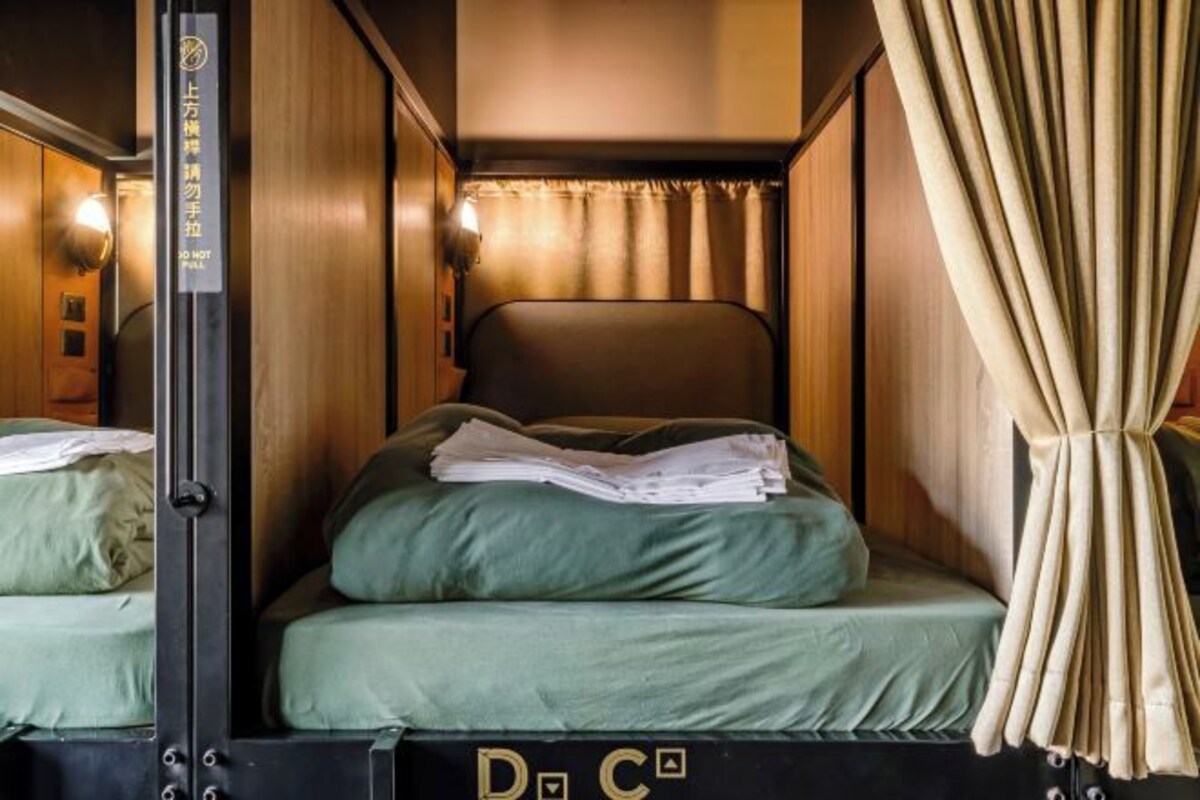 A compact train compartment with a single bed, a small table, and a curtain.