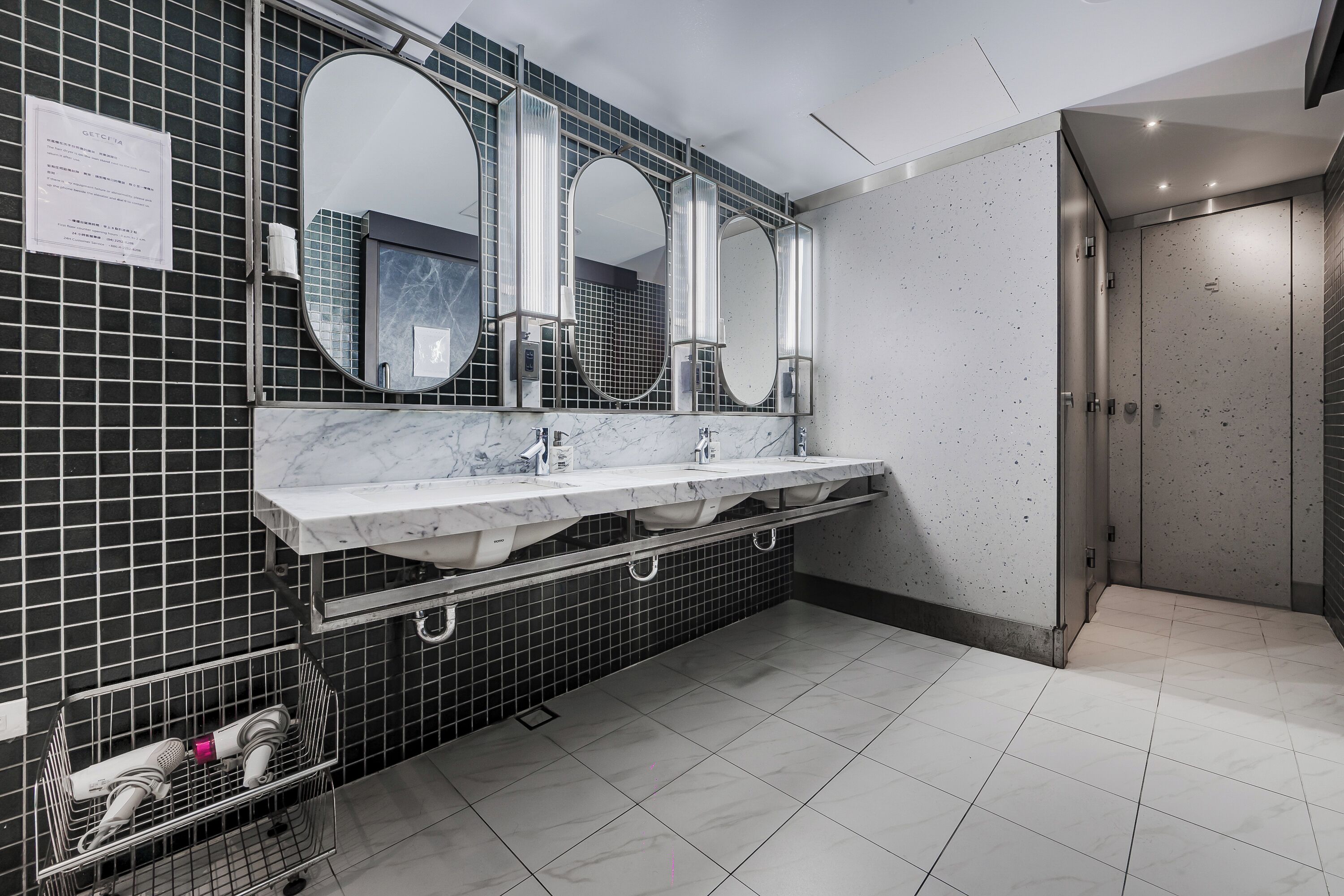 Un baño moderno con un espejo grande, dos lavamanos y piso de baldosas.