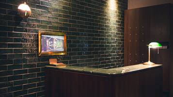 A reception area with a dark brick wall, a framed picture, a counter, and a green desk lamp.