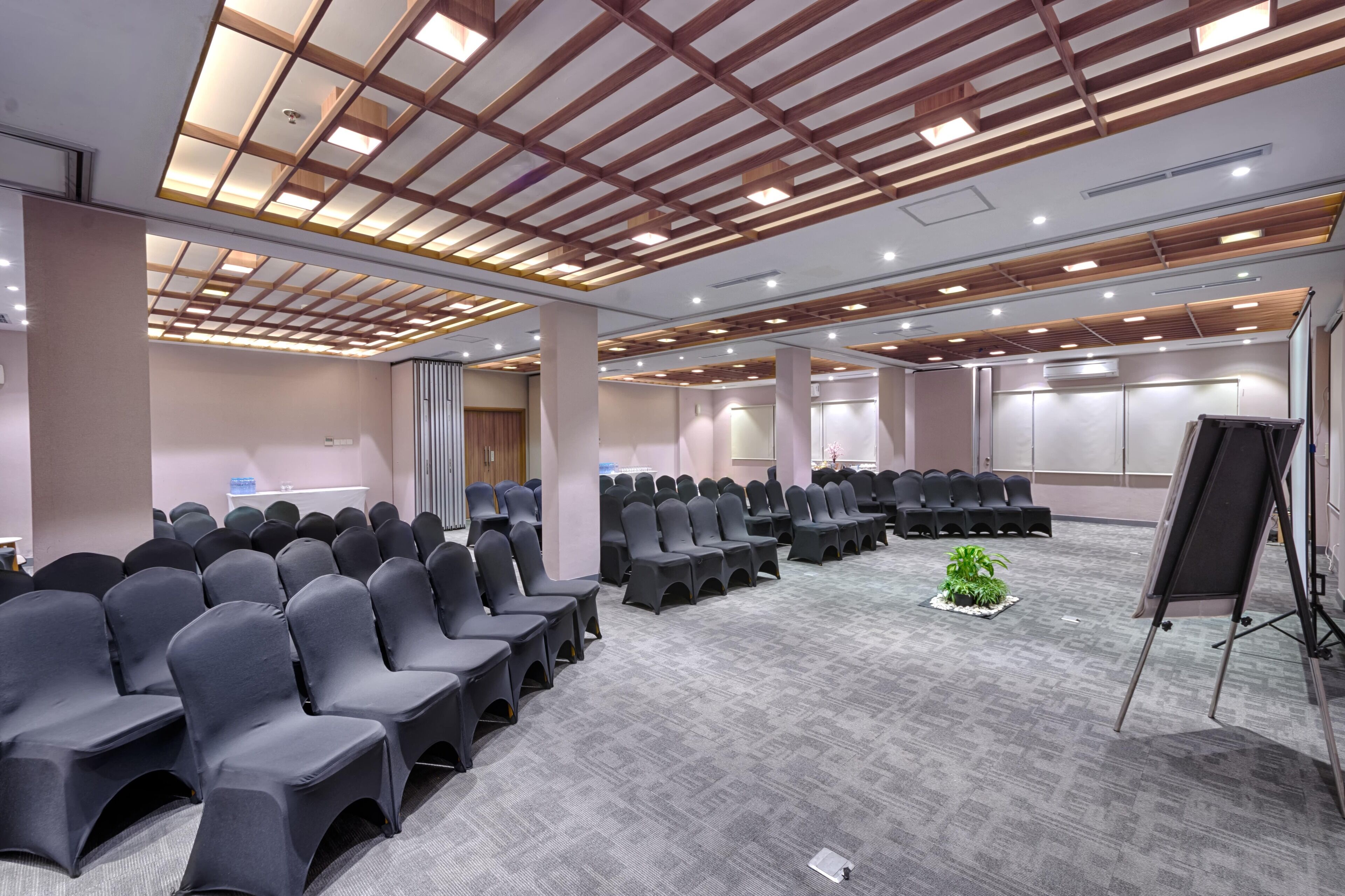 A conference room with rows of chairs, a projector screen, and a carpeted floor.