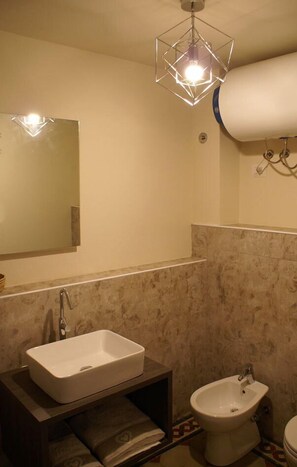 A bathroom with a rectangular sink, a bidet, a mirror, and a geometric light fixture. - B&B Garibaldi (Pisa)