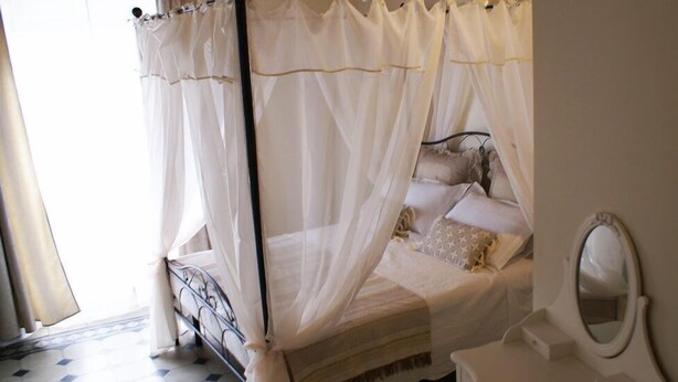 A bedroom with a four-poster bed, a bedside table, and a mirror. - B&B Garibaldi (Pisa)