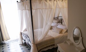 A bedroom with a four-poster bed, a bedside table, and a mirror. - B&B Garibaldi (Pisa)