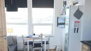 Une cuisine compacte comprenant un coin repas, un réfrigérateur et un téléviseur fixé au mur.