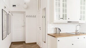 A modern kitchen with white cabinetry, a wooden countertop, and a stainless steel sink. - AP-Apartments Górnośląska No. 24 (Warsaw)