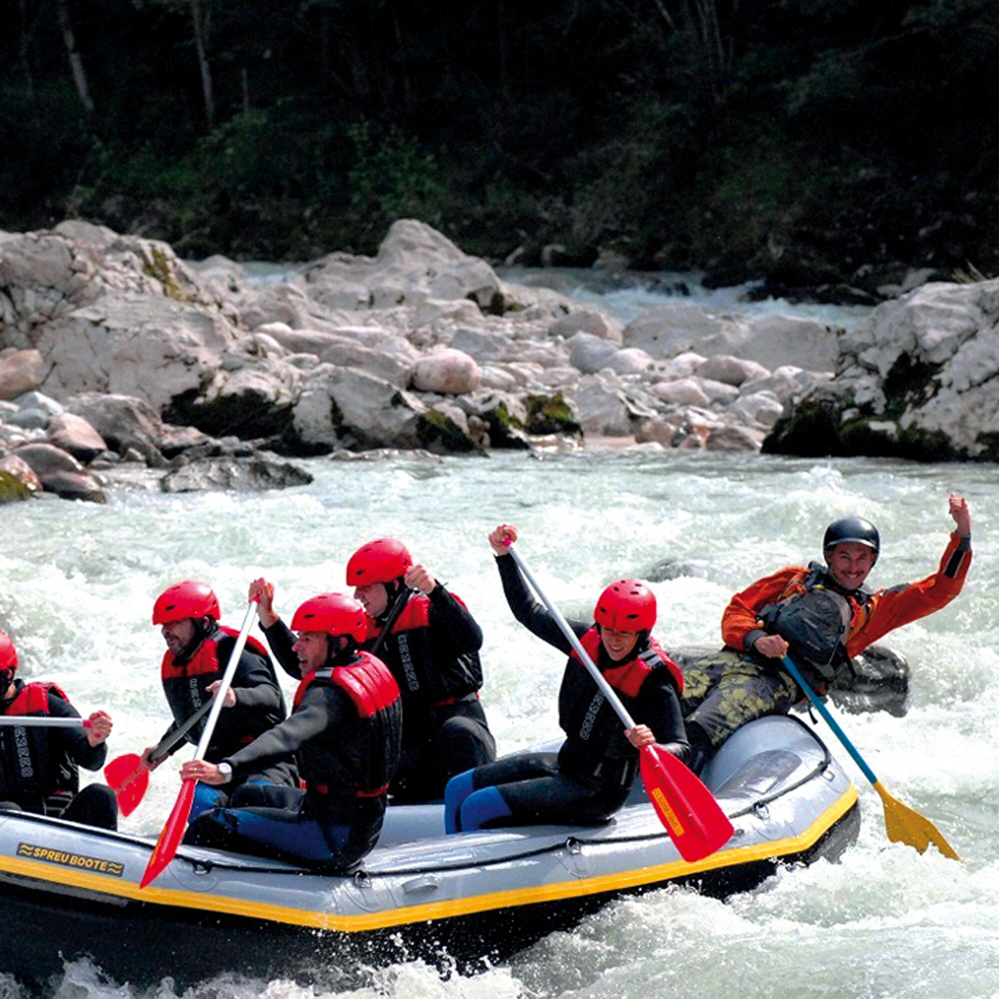 A group of people in a raft navigating a river surrounded by rocks and trees.