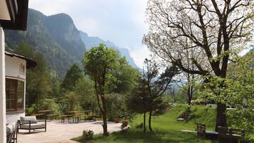 Un patio con mobiliario exterior, un sendero de piedra y vistas a montañas.