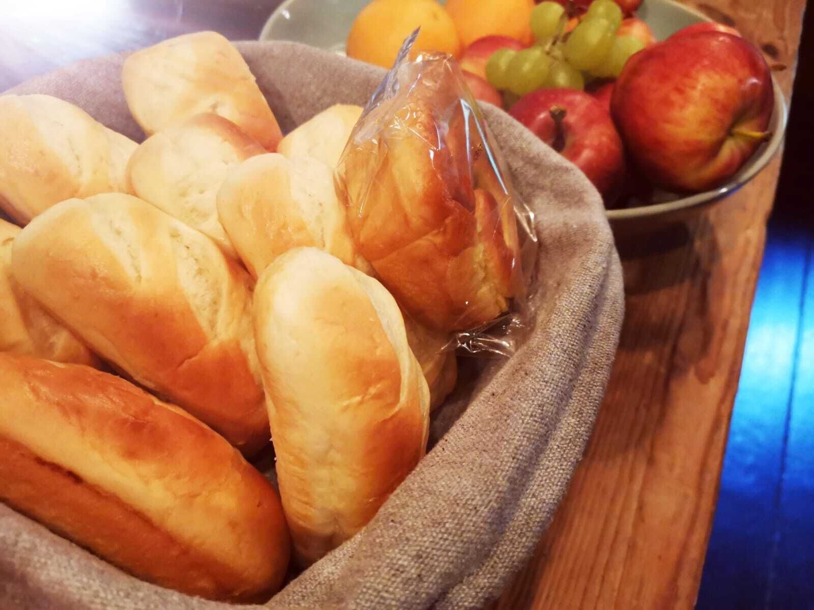 A basket of freshly baked bread rolls on a wooden table.