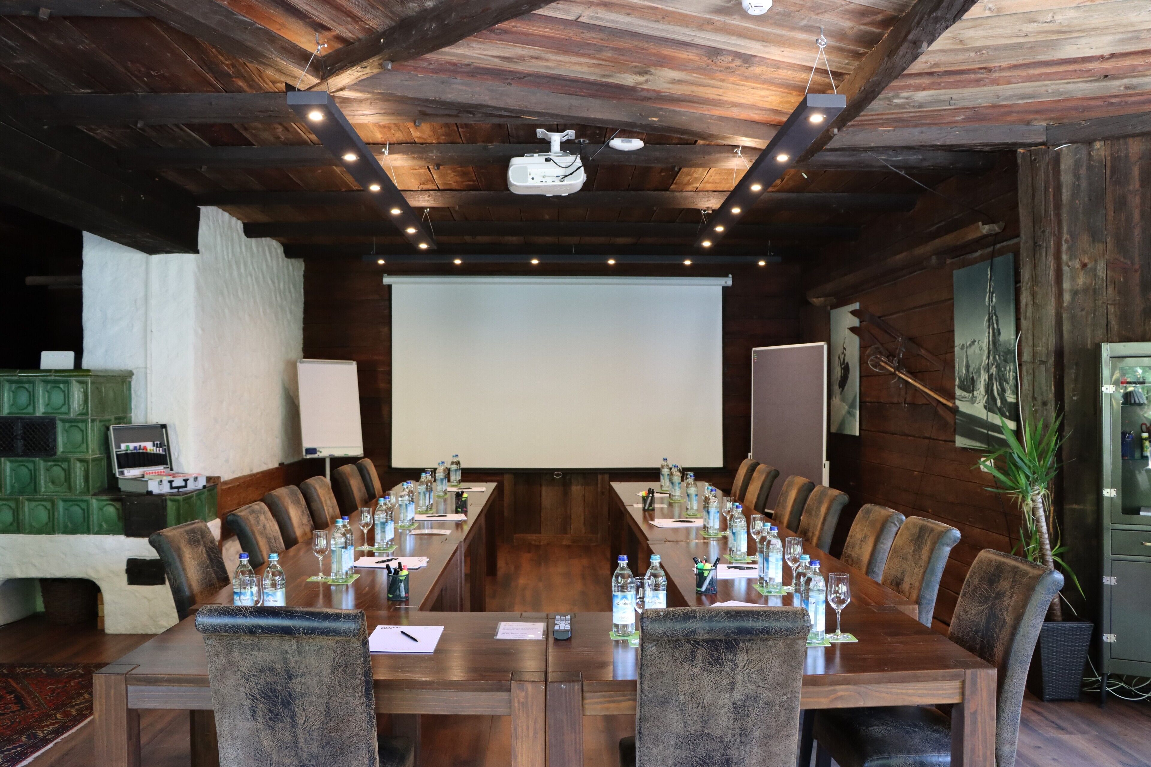 Un salón de conferencias con una larga mesa, sillas, un proyector y una pantalla.