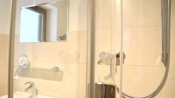 A bathroom with a glass-enclosed shower, a sink with a chrome faucet, and a mirror above the sink.